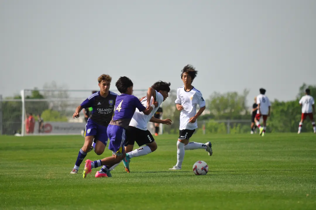 Youth soccer players battling for the ball on a wide field