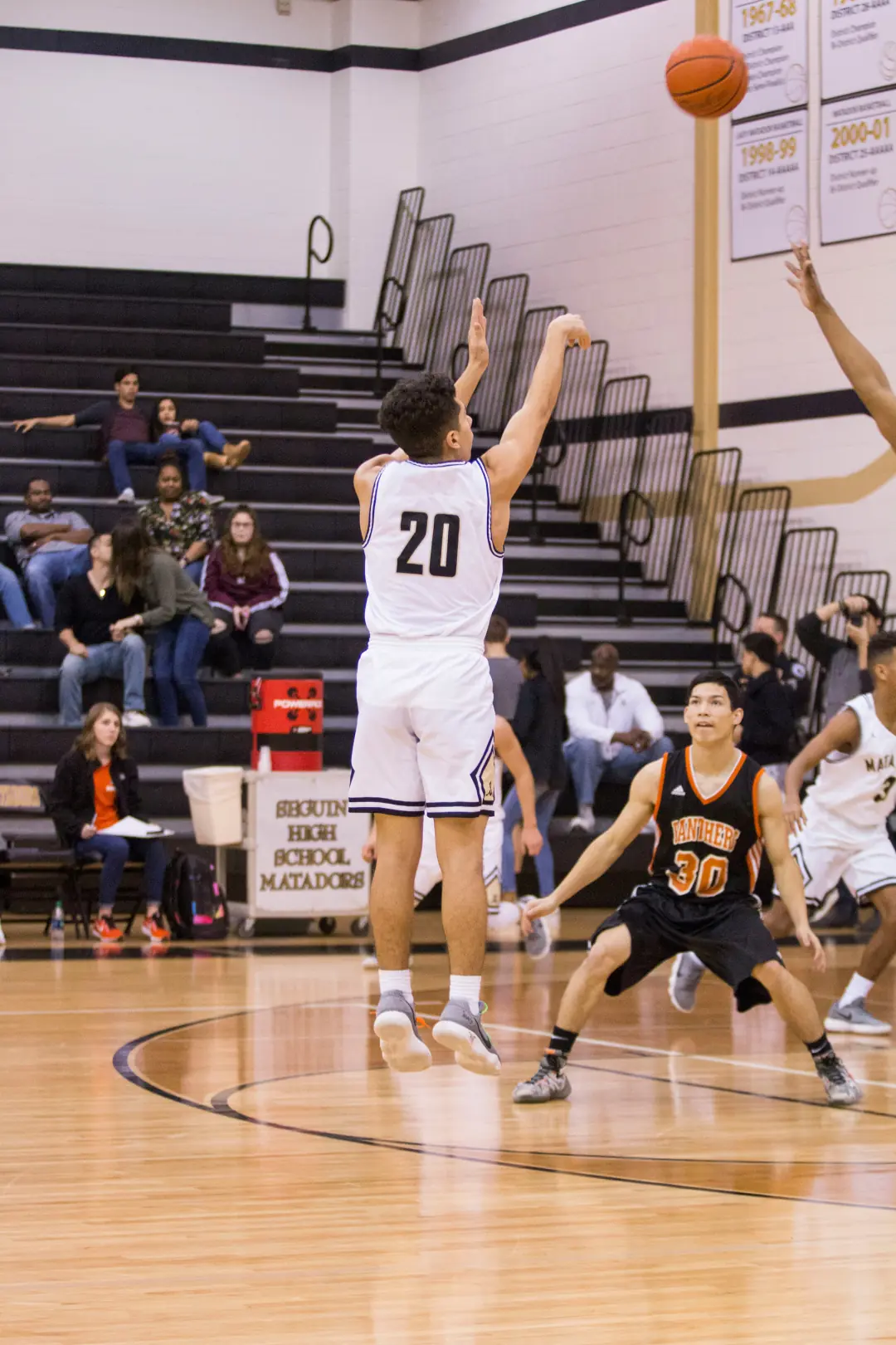 High school basketball player taking a jump shot in a packed gym