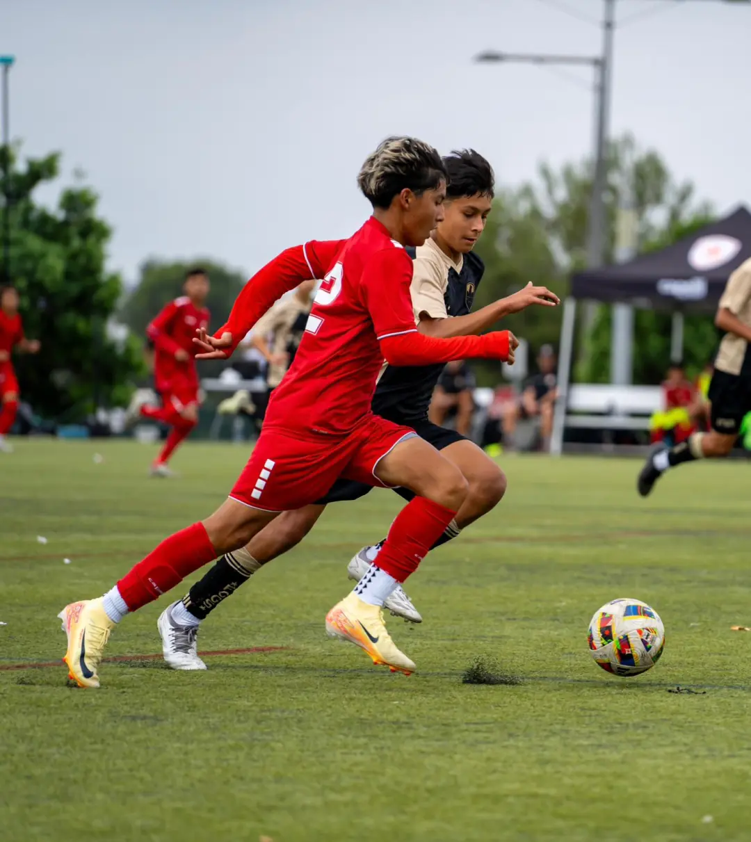 Two youth soccer players racing side by side for the ball