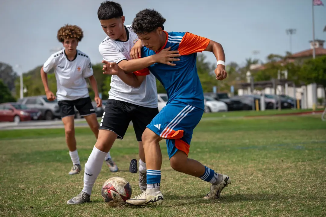 Three players fighting for the ball in a tackle