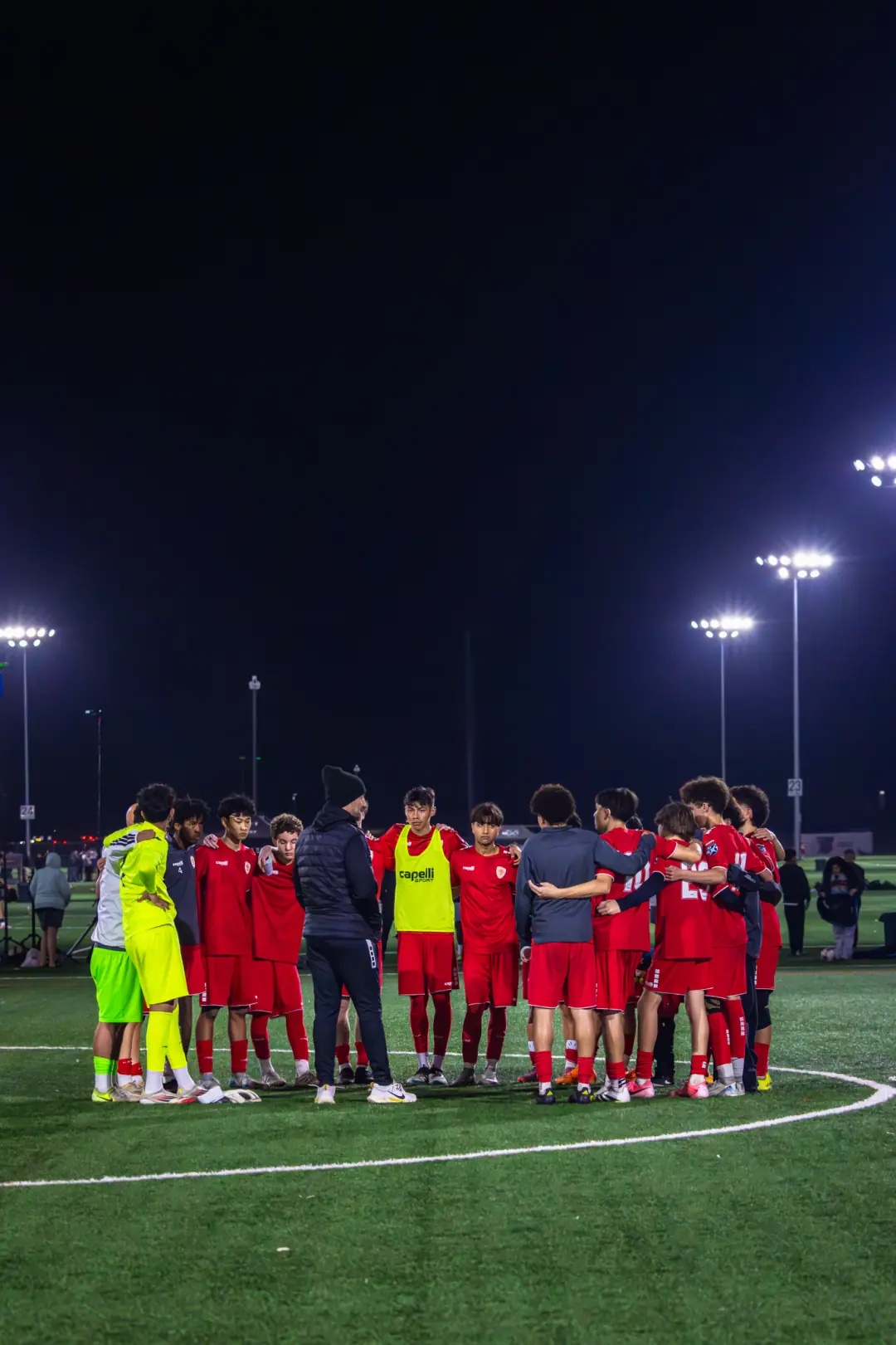 Soccer team in a huddle under the stadium lights